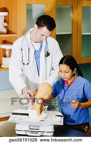 Girl examining a doll with a stethoscope and a male doctor standing beside her View Large Photo Image Stock Photo - Girl examining a doll with a stethoscope and a male doctor standing beside her. Fotosearch