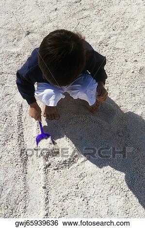 High angle view of a boy playing in the sand View Large Photo Image Stock Photograph - High angle view of a boy playing in the sand. Fotosearch