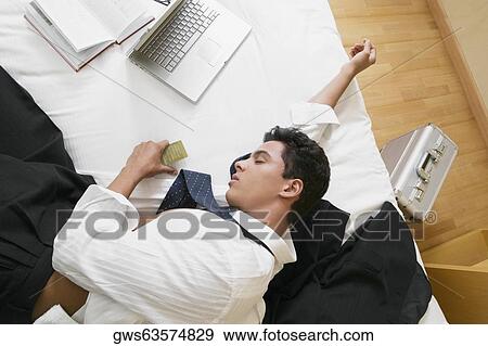 High angle view of a businessman sleeping on the bed View Large Photo Image Stock Photo - High angle view of a businessman sleeping on the bed. Fotosearch