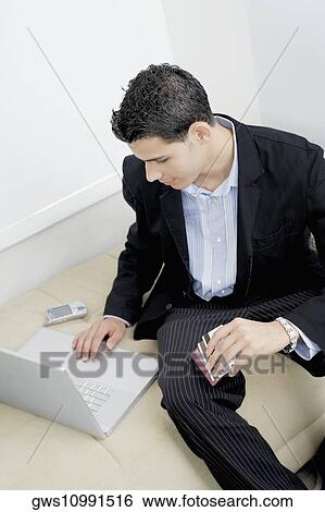Stock Photograph - High angle view of a businessman using a laptop on a couch. Fotosearch