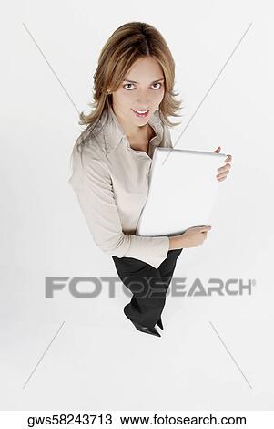 Stock Image - High angle view of a businesswoman holding a laptop and smiling. Fotosearch