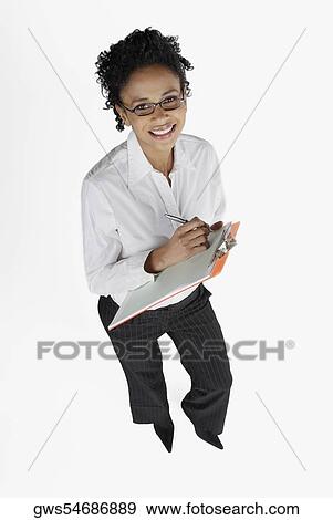 Stock Photo - High angle view of a businesswoman holding a clipboard and smiling. Fotosearch