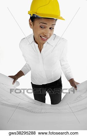 Stock Photo - High angle view of a female architect holding a blueprint and making a face. Fotosearch