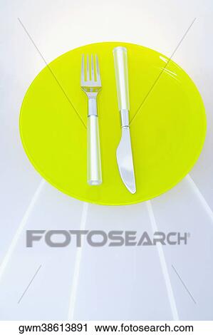 Stock Image - High angle view of a fork with a table knife on a plate. Fotosearch