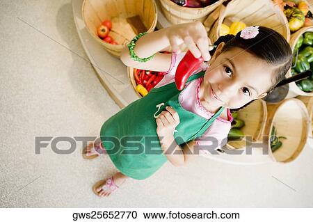 Stock Image - High angle view of a girl holding a red chili pepper. Fotosearch