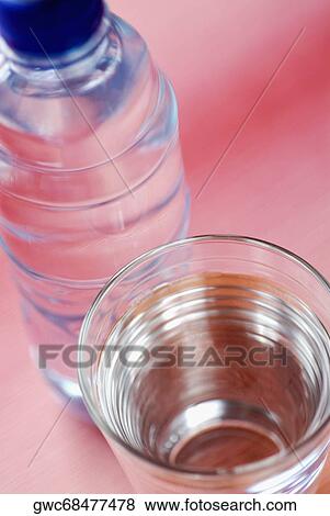 Stock Photo - High angle view of a glass of water with a water bottle. Fotosearch