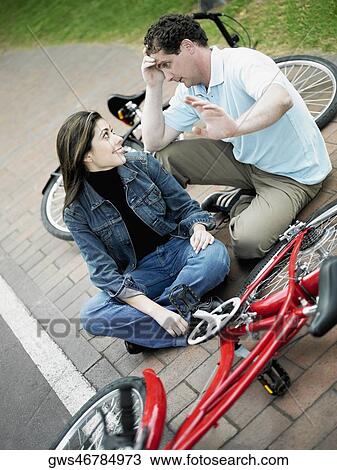 Stock Image - High angle view of a mid adult couple sitting with bicycles and looking at each other. Fotosearch
