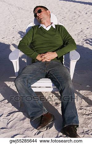 Picture - High angle view of a mid adult man reclining on a lounge chair. Fotosearch