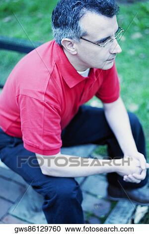 High angle view of a mid adult man sitting on a bench View Large Photo Image Stock Image - High angle view of a mid adult man sitting on a bench. Fotosearch