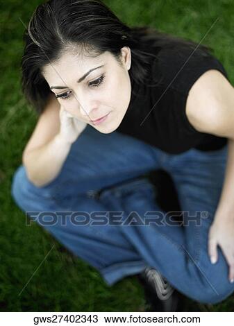 Stock Image - High angle view of a mid adult woman sitting on a lawn. Fotosearch
