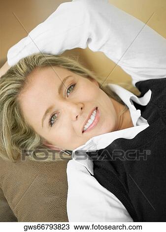 High angle view of a mid adult woman lying on a couch and smiling View Large Photo Image Stock Image - High angle view of a mid adult woman lying on a couch and smiling. Fotosearch