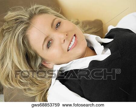 High angle view of a mid adult woman lying on a couch and smiling View Large Photo Image Stock Photo - High angle view of a mid adult woman lying on a couch and smiling. Fotosearch