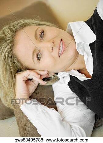 High angle view of a mid adult woman lying on a couch and smiling View Large Photo Image Stock Photo - High angle view of a mid adult woman lying on a couch and smiling. Fotosearch