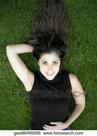 Stock Photograph - High angle view of a mid adult woman lying on a lawn. Fotosearch