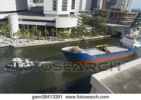 Stock Image - High angle view of a tugboat pulling a container ship. Fotosearch