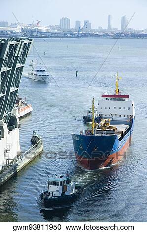 Stock Image - High angle view of a tugboat pulling a cargo container. Fotosearch