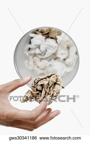 High angle view of a woman's hand throwing a crumpled sheet of paper in a wastepaper basket View Large Photo Image Stock Photograph - High angle view of a woman's hand throwing a crumpled sheet of paper in a wastepaper basket. Fotosearch