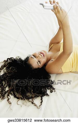 High angle view of a young woman lying on the bed and operating a mobile View Large Photo Image Stock Image - High angle view of a young woman lying on the bed and operating a mobile. Fotosearch
