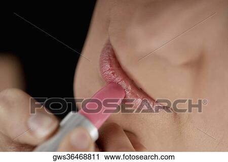 High angle view of a young woman applying lipstick View Large Photo Image Stock Image - High angle view of a young woman applying lipstick. Fotosearch