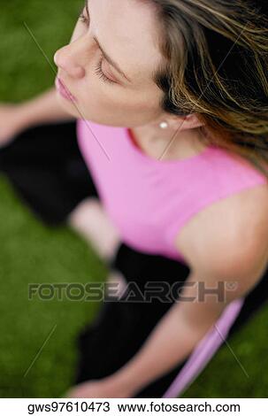 Stock Image - High angle view of a young woman sitting in the lotus position. Fotosearch