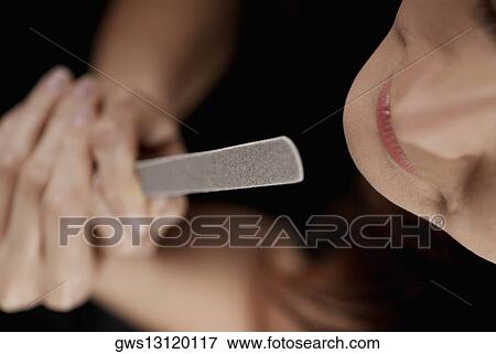 Stock Photo - High angle view of a young woman holding a nail file. Fotosearch