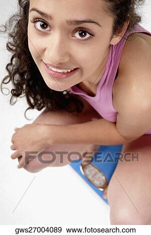 High angle view of a young woman crouching on a weight scale View Large Photo Image Stock Photo - High angle view of a young woman crouching on a weight scale. Fotosearch