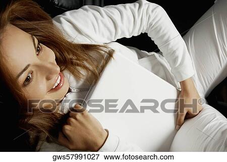 Stock Photo - High angle view of a young woman hugging her laptop. Fotosearch