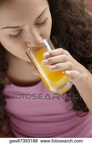 Stock Photo - High angle view of a young woman drinking a glass of juice. Fotosearch