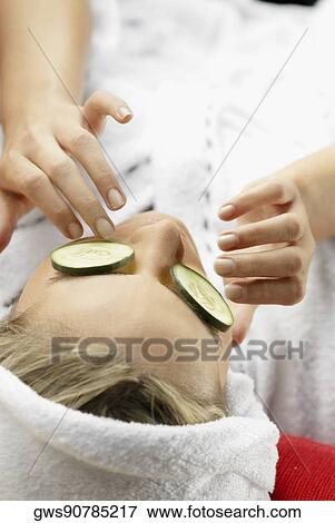 Stock Photo - High angle view of a young woman with cucumber slices on her eyes. Fotosearch