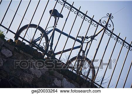 Low angle view of a bicycle leaning against a railing View Large Photo Image Picture - Low angle view of a bicycle leaning against a railing. Fotosearch