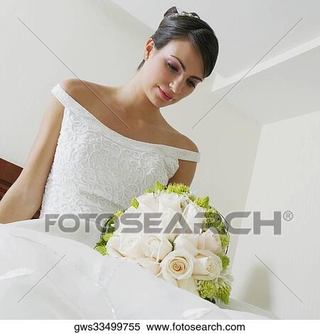 Low angle view of a bride looking at a bouquet of flowers View Large Photo Image Stock Photography - Low angle view of a bride looking at a bouquet of flowers. Fotosearch