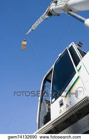 Low angle view of a crane carrying a cargo container View Large Photo Image Stock Image - Low angle view of a crane carrying a cargo container. Fotosearch
