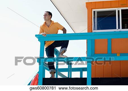 Low angle view of a mid adult man leaning against a railing of a lifeguard hut View Large Photo Image Stock Image - Low angle view of a mid adult man leaning against a railing of a lifeguard hut. Fotosearch