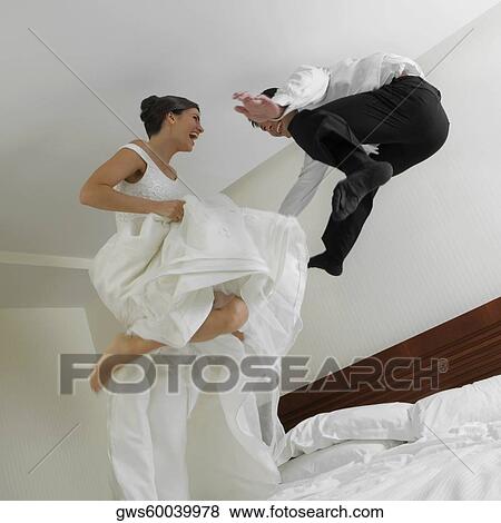Low angle view of a newlywed couple jumping on the bed View Large Photo Image Stock Photo - Low angle view of a newlywed couple jumping on the bed. Fotosearch