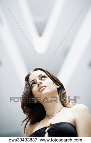 Low angle view of a young woman looking serious View Large Photo Image Stock Photo - Low angle view of a young woman looking serious. Fotosearch