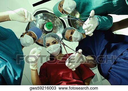 Low angle view of three male surgeons and a female surgeon holding surgical equipments View Large Photo Image Stock Image - Low angle view of three male surgeons and a female surgeon holding surgical equipments. Fotosearch