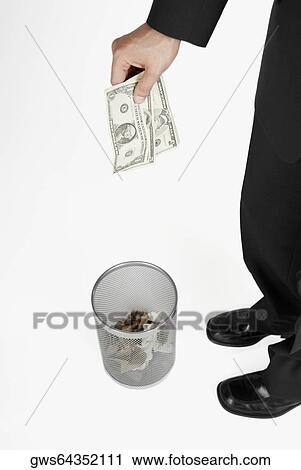 Low section view of a businessman throwing paper currency into a wastepaper basket View Large Photo Image Stock Image - Low section view of a businessman throwing paper currency into a wastepaper basket. Fotosearch