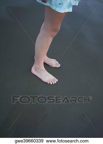 Stock Photo - Low section view of a girl standing on the beach. Fotosearch