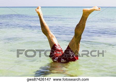 Low section view of a man doing a handstand in the sea View Large Photo Image Stock Photo - Low section view of a man doing a handstand in the sea. Fotosearch