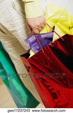 Low section view of a man holding shopping bags View Large Photo Image Stock Image - Low section view of a man holding shopping bags. Fotosearch
