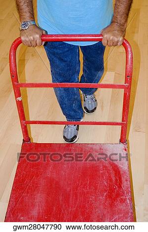 Stock Image - Low section view of a man pushing a trolley. Fotosearch