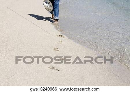 Low section view of a person walking on the beach View Large Photo Image Stock Photograph - Low section view of a person walking on the beach. Fotosearch