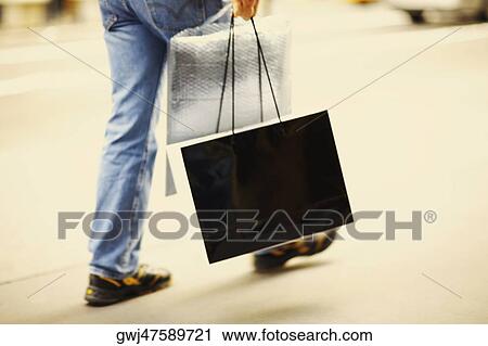 Low section view of a person walking and carrying a shopping bag View Large Photo Image Stock Image - Low section view of a person walking and carrying a shopping bag. Fotosearch