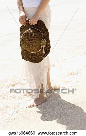 Low section view of a young woman holding a sunhat on the beach View Large Photo Image Stock Image - Low section view of a young woman holding a sunhat on the beach. Fotosearch