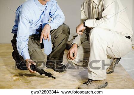 Picture - Low section view of two male architects crouching on a hardwood floor. Fotosearch