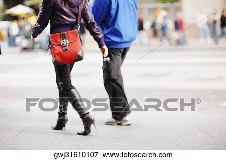 Stock Photo - Low section view of two people walking and carrying bags. Fotosearch
