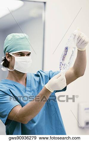 Stock Photo - Male surgeon holding an IV drip bag. Fotosearch