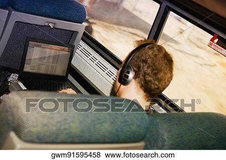 Man in a train using a laptop and listening to music in a train View Large Photo Image Stock Photo - Man in a train using a laptop and listening to music in a train. Fotosearch
