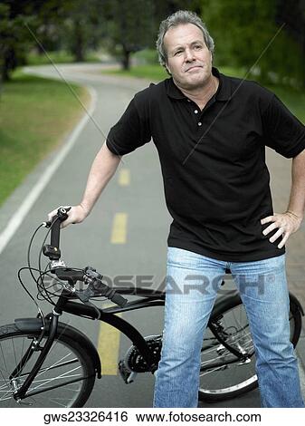 Mature man standing with a bicycle View Large Photo Image Stock Photograph - Mature man standing with a bicycle. Fotosearch