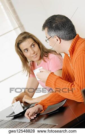 Mid adult couple holding two cups of coffee View Large Photo Image Stock Photo - Mid adult couple holding two cups of coffee. Fotosearch